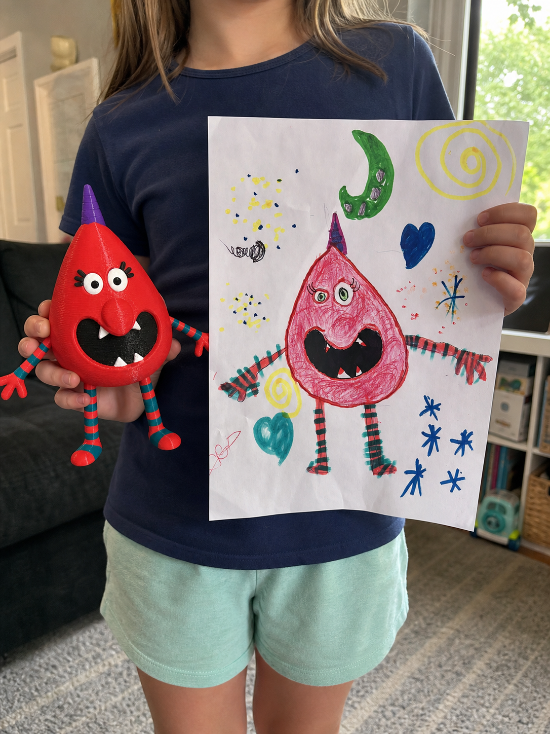 A child holding their original monster drawing beside the matching 3D-printed Artwork Figure